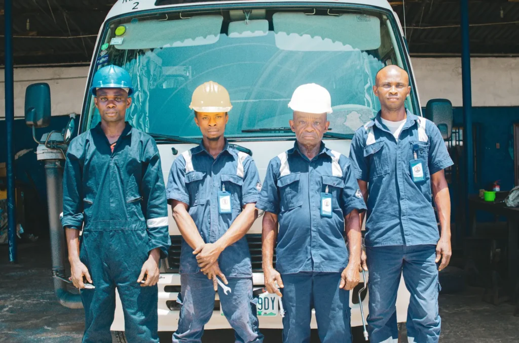 Team of technicians in coveralls and hard hats in a vehicle workshop